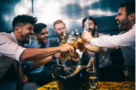 a group of guys toasting beers and smiling