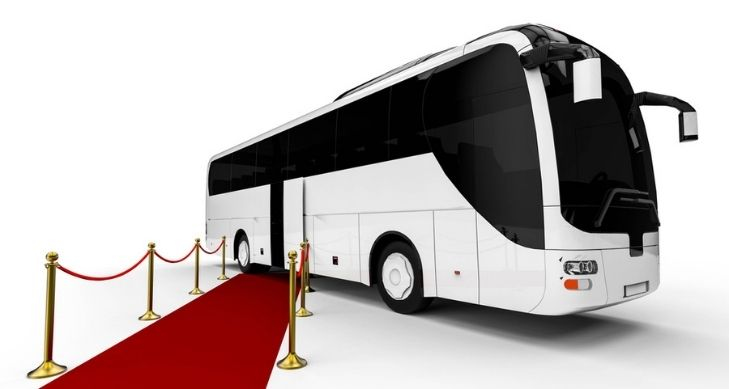 large party bus motorcoach with red carpet leading to door