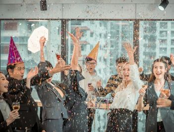 professionals cheering and throwing confetti at a modern office party