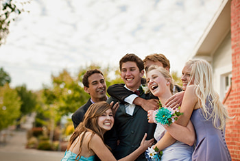 A group of teens pose for prom pictures outside a suburban home