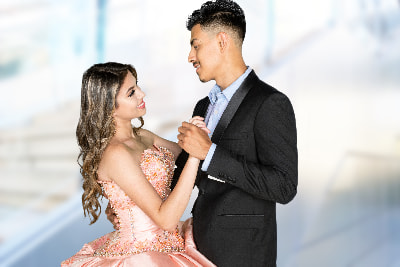 A girl in a fancy pink dress dances with a young man 